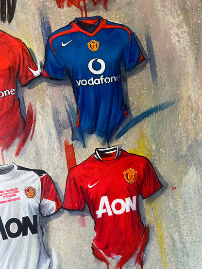 Man United 2022 artwork by Terry Kneeshaw - 20 iconic jerseys A2 limited edition print could be: A limited edition A2 print featuring 20 iconic Manchester United jerseys from the club's history. The jerseys are arranged in a grid-like pattern, showcasing a range of home and away kits from different eras. Some of the notable jerseys include the classic red and white home kit, the black away kit from the 1990s, and the blue and white third kit from the 2010s.